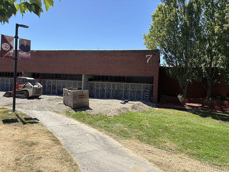 The exterior of Building 7 with gravel covering a walkway and construction equipment.