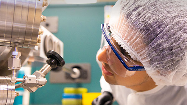 A person in a clean room looking at instrumention.